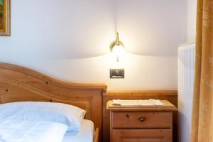 a bedroom with a bed and a lamp on a nightstand at Hotel Residence Gardena Sella in Santa Cristina Gherdëina