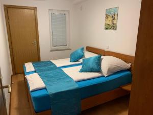 a bedroom with a bed with blue and white pillows at Apartmani Auer in Pješčana Uvala