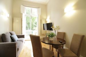 ein Wohnzimmer mit Tisch und Stühlen und einem Fernseher in der Unterkunft Queen Victoria Apartments in London