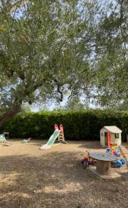 a playground with a slide and play equipment under a tree at Casale Torre San Magno in Corato