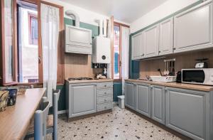 ヴェネツィアにあるAppartamento Ai Greci Residenza Quaggioのキッチン(グレーのキャビネット、白い電化製品付)