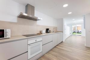 a kitchen with white appliances and wooden floors at Albercutx Pollentia 2 in Port de Pollensa
