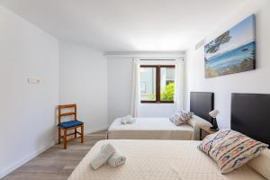 een witte kamer met 2 bedden en een stoel bij Albercutx Pollentia 2 in Port de Pollença