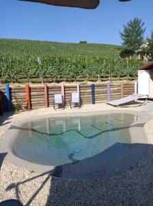 a swimming pool with two chairs and a fence at Vitae di Langa in Grinzane Cavour