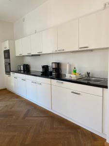 uma cozinha com armários brancos e bancadas pretas em grosszügiges Apartment mit Blick zur Frauenkirche em Dresden