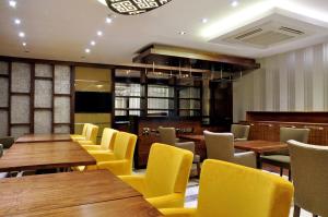 a restaurant with wooden tables and yellow chairs at Avin Hotel in İzmir