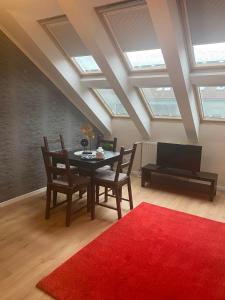 a living room with a table and chairs and a red rug at Lucsony Apartman in Mosonmagyaróvár