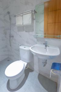 a bathroom with a white toilet and a sink at Genio Inn - MANTOS in Manado