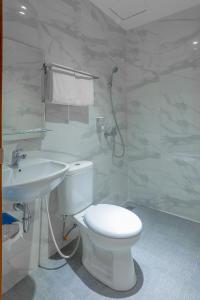 a white bathroom with a toilet and a sink at Genio Inn - MANTOS in Manado