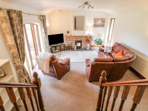 a living room with leather furniture and a fireplace at The Cottage in Mapperley