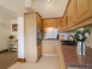 a kitchen with wooden cabinets and a vase of flowers at The Cottage in Mapperley