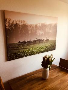 a painting on a wall with a vase of flowers at Urlaub auf Mittelhof in Großenbrode