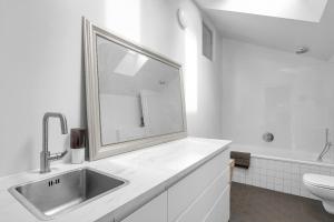 Baño blanco con lavabo y espejo en Sunny Apartment in the Reykjavík City Center, en Reikiavik
