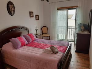 um quarto com uma cama grande e almofadas rosa e roxa em MARIA INÊS HOUSE em Nazaré