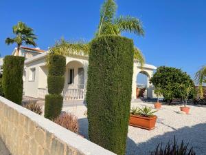 a house with a hedge in front of a wall at Coral Bungalow in Coral Bay