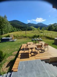 a wooden deck with benches and tables in a field at Tubej superior wellness house in Bohinj