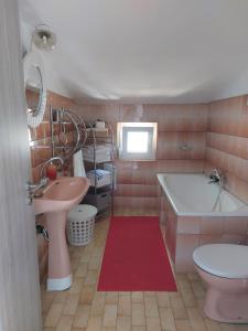a pink bathroom with a tub and a sink and a bath tub at Popi 2 in Klenovica