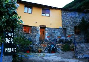 una casa de piedra con un cartel delante en Casa Rural La Fuente, en Tejedo del Sil