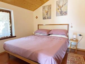 una camera da letto con un letto con lenzuola rosa e una finestra di Appartamento con Terrazzo Panoramico vicino al Centro di Folgaria a Folgaria