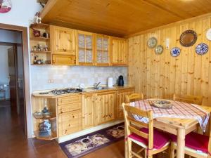 una cocina con armarios de madera, mesa y fregadero en Appartamento con Terrazzo Panoramico vicino al Centro di Folgaria, en Folgaria