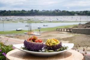 a plate of vegetables on a table with a view of a beach at Hôtel De La Vallée in Dinard
