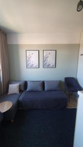 a blue couch in a room with two pictures on the wall at Loft Rooms - Apartamenty w Kamienicy centrum, bezpłatny parking in Ełk +23 photos