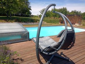 a swing chair on a deck next to a pool at Au chant des oiseaux in Hennecourt +6 photos