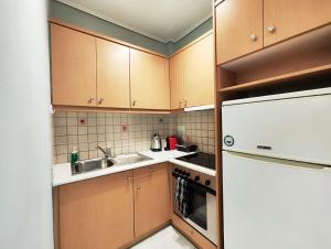 a kitchen with wooden cabinets and a sink and a refrigerator at Veno Donwtown in Athens