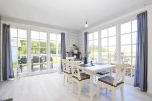 a white dining room with a white table and chairs at Redewisch Lee und Luv Ferienwohnung Luv in Redewisch