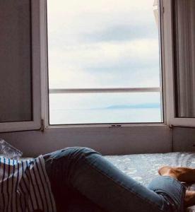 a person laying on a bed looking out of a window at Respirando salitre apartamento en Lastres in Lastres +24 photos
