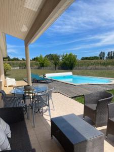 un patio con mesa y sillas y una piscina en Villa familiale les coteaux de ruelle, en Tonneins