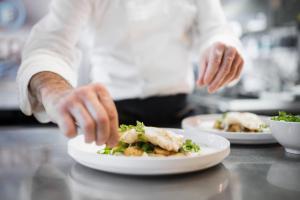 a chef preparing a plate of food on a counter at Hôtel De La Vallée in Dinard