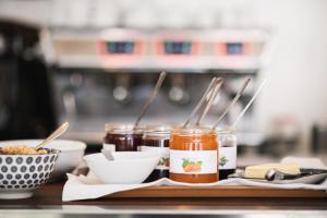a table with jars of jam and a bowl of food at Hôtel De La Vallée in Dinard