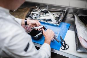 a man cutting fish with a pair of scissors at Hôtel De La Vallée in Dinard