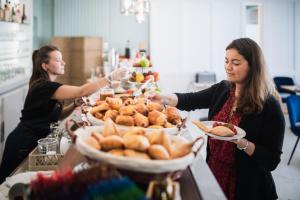 two women are serving food at a buffet at Hôtel De La Vallée in Dinard