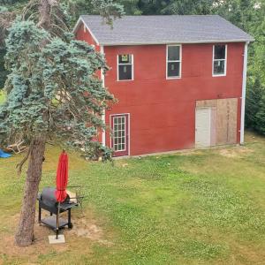 a red house with a chair next to a tree at Room in Cabin - Camping Cabin With Sauna Access 2nd Fl- in Dover