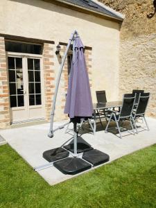 un parapluie violet, une table et des chaises dans l'établissement Centre ville (1) : superbe appartement climatisé, à La Flèche