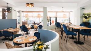 a restaurant with wooden tables and blue chairs at Hôtel De La Vallée in Dinard