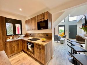 a kitchen with wooden cabinets and a living room at Duplex Design 6P - accès jardin et parking gratuit in Malakoff