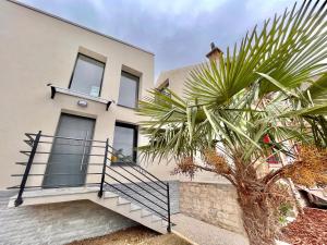 a house with a palm tree in front of it at JO 2024 - 4km Porte de Versailles - Duplex 6P - jardin et parking gratuit in Malakoff