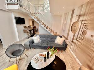 a living room with a couch and a staircase at Duplex Design 6P - accès jardin et parking gratuit in Malakoff