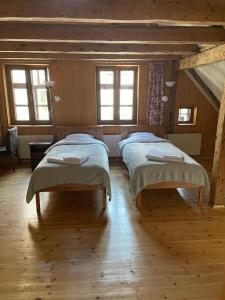 two beds in a room with wooden floors and windows at Kapteinis in Liepāja