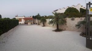 a driveway with palm trees next to a wall at Casa vacanze immersa nelle campagne salentine in Monacizzo +6 photos