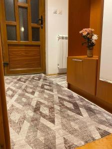 a hallway with a door and a carpet with a vase of flowers at White Home in Žabljak