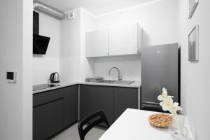 a kitchen with a table and a sink and a refrigerator at Golden Apartments/Op25 in Katowice