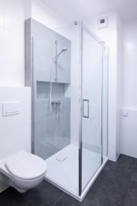 a white bathroom with a shower and a toilet at Golden Apartments/Op25 in Katowice
