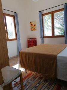 a bedroom with a bed and two windows and a chair at Gîte Les Romarins in Saint-Jean-de-Minervois