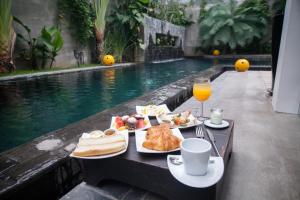 a table with food and drinks next to a swimming pool at Arthur & Paul (Men Only Hotel) in Phnom Penh