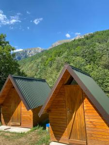 a couple of wooden buildings with mountains in the background at Apartmani Sastavci in Tjentište
