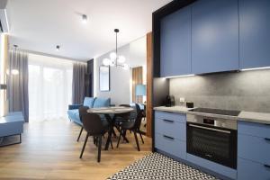 a kitchen and dining room with blue cabinets and a table at Apartamenty LookAp Ustronie Morskie I przy plaży in Ustronie Morskie